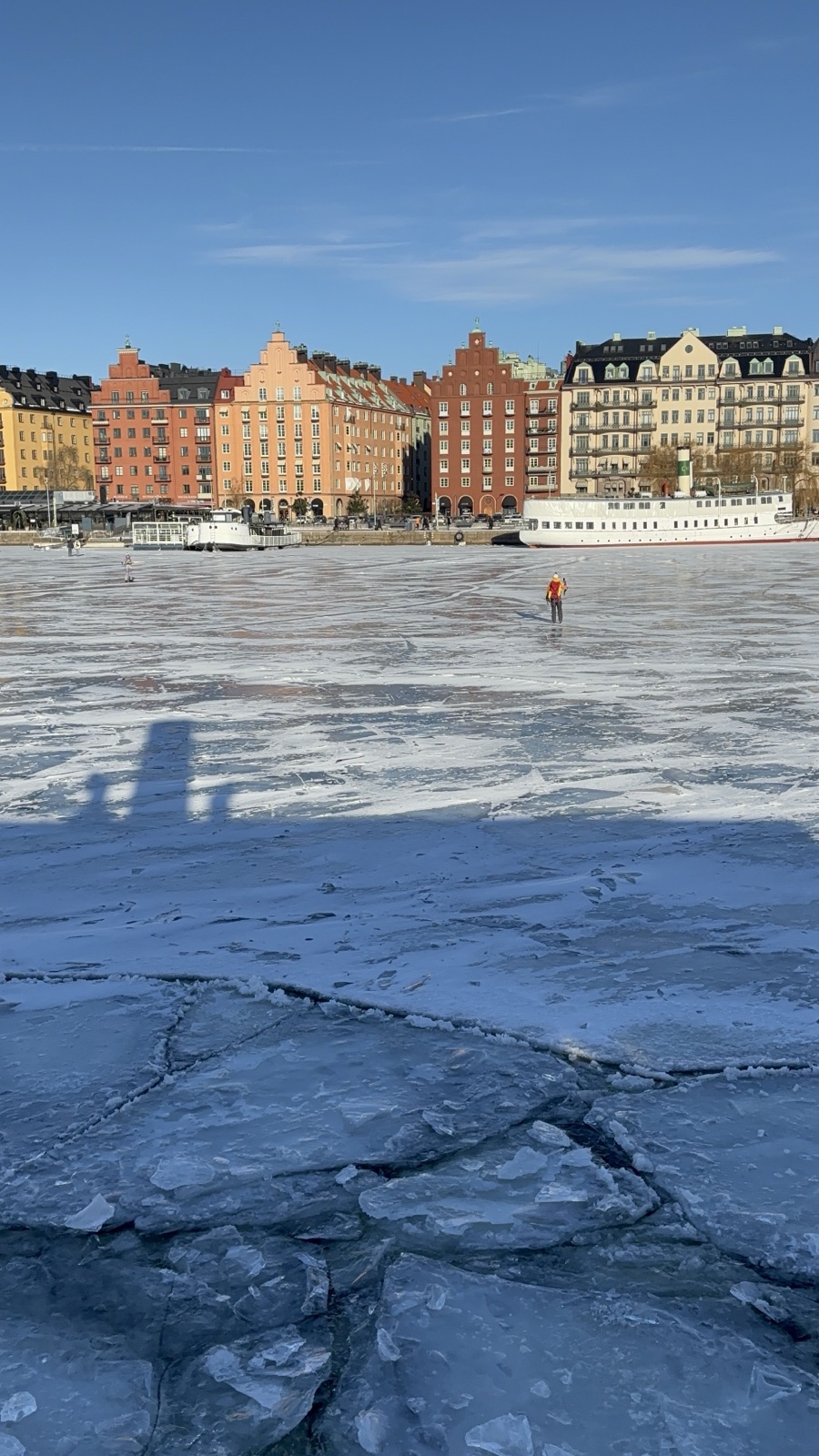 Cracked ice near the shore, and the city just across it.